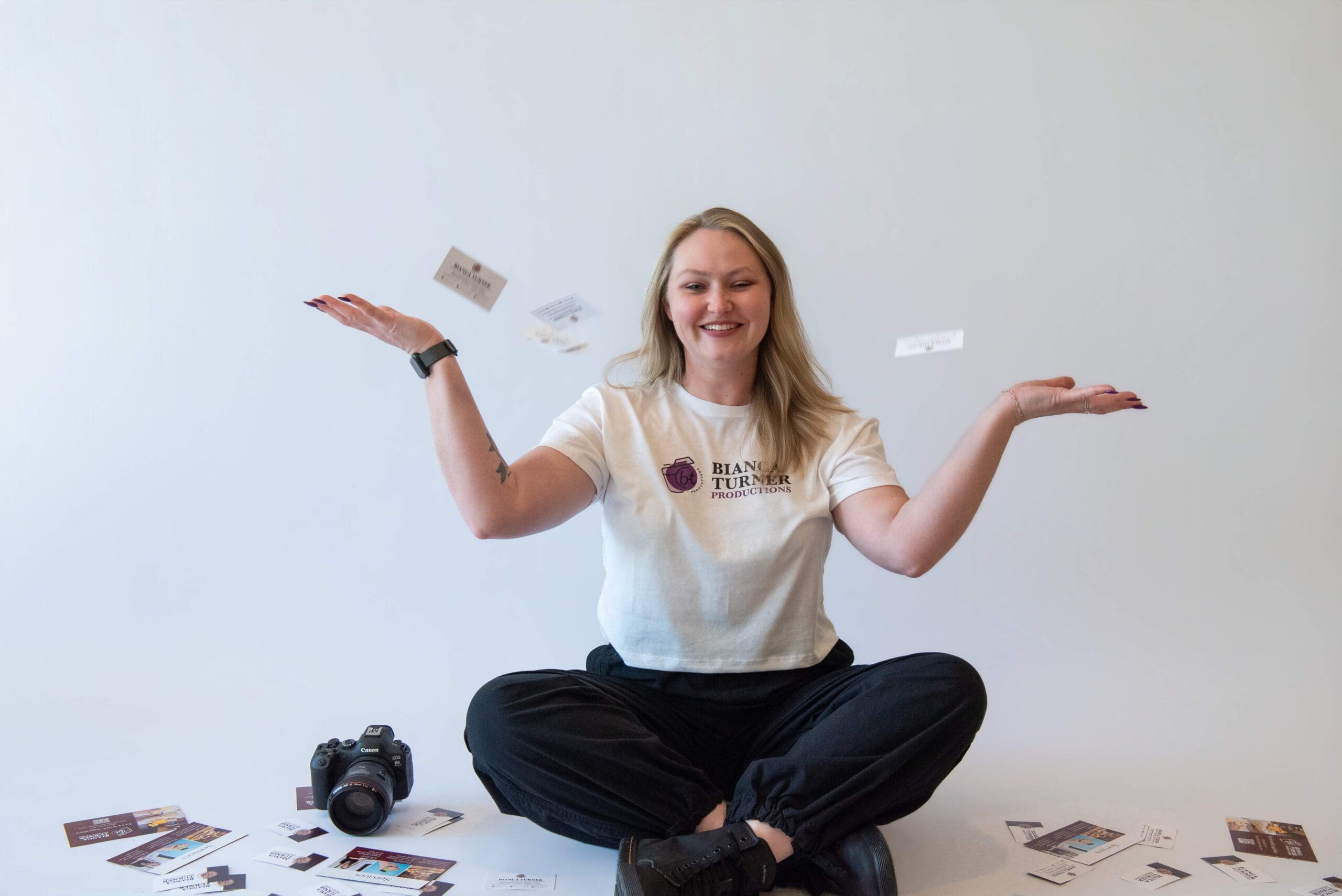Bianca sitting in a white background throwing business cards in the air.