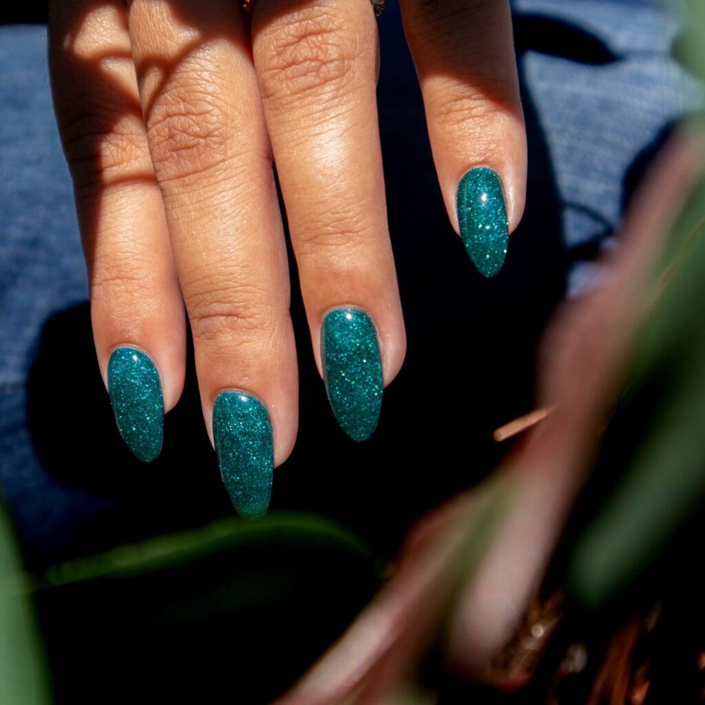 A female model with green jewell gel polish on a Fall photo set.